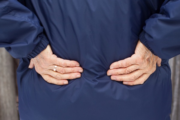 Elderly woman holding her back in pain with arthritis - Hosford Health Clinic