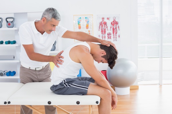 Hosford Health Clinic osteopath examining spinal alignment of male patient