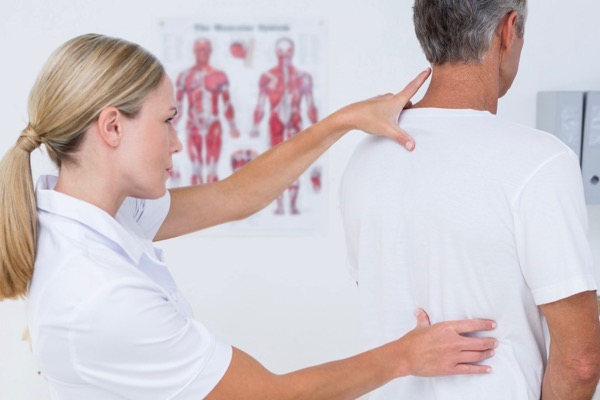 Osteopath examining a patient standing with headache, neck and shoulder pain