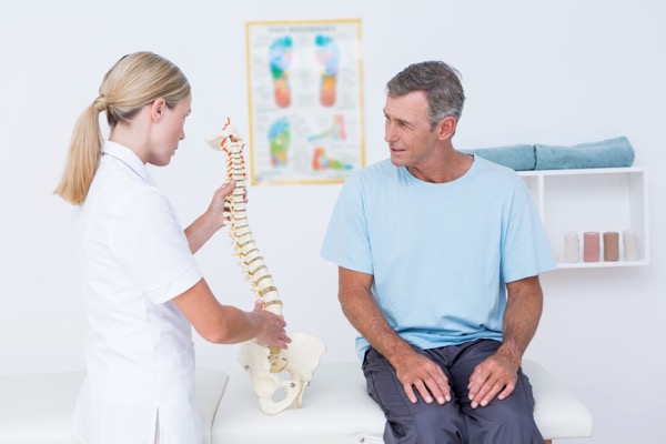 Hosford Health Clinic osteopath pointing at spine of male patient sitting