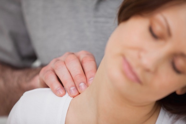 Osteopath stretching neck of a supine patient with headache, neck and shoulder pain